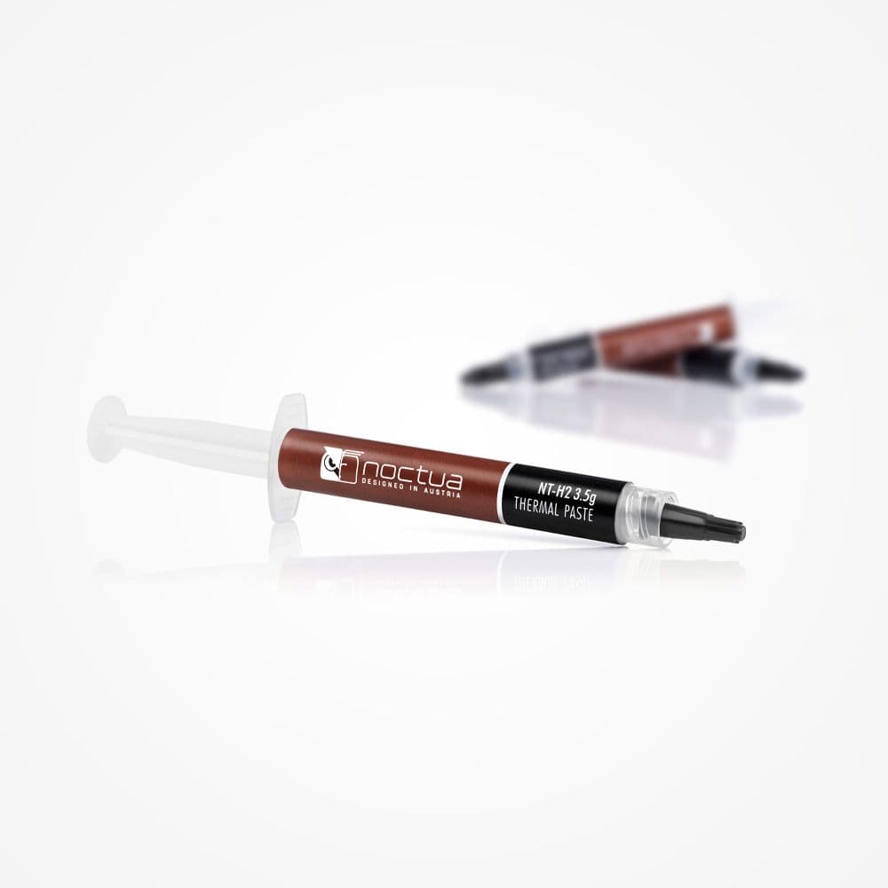 An angled shot of a syringe of Noctua NT-H2 3.5g thermal paste on a reflective white surface, with two syringes in the background.