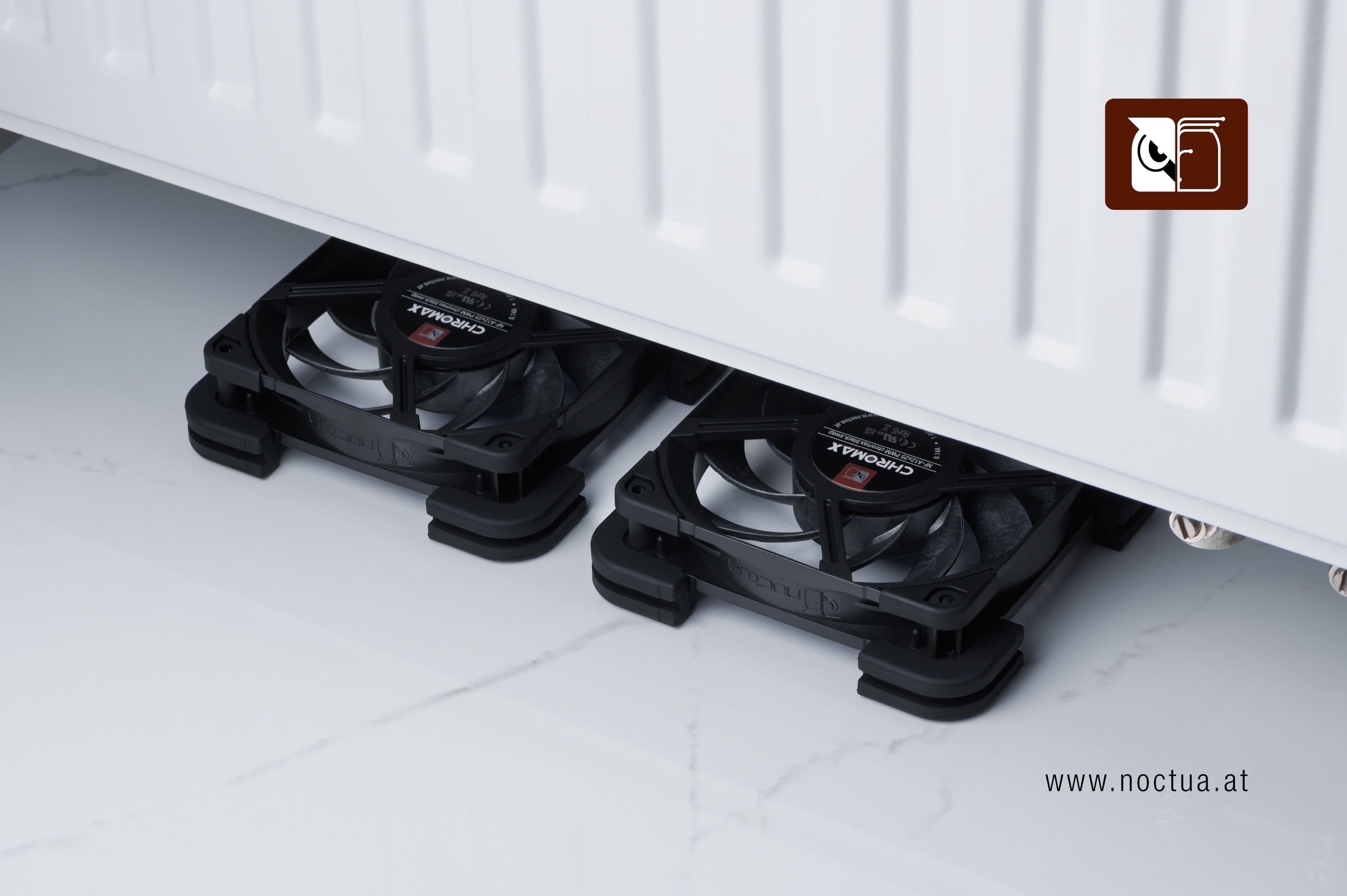 Two chromax.black Noctua NF-A12x25 fans equipped with NV-MPG1 gaskets and NV-MPP pads placed underneath a household radiator, demonstrating active radiator ventilation.