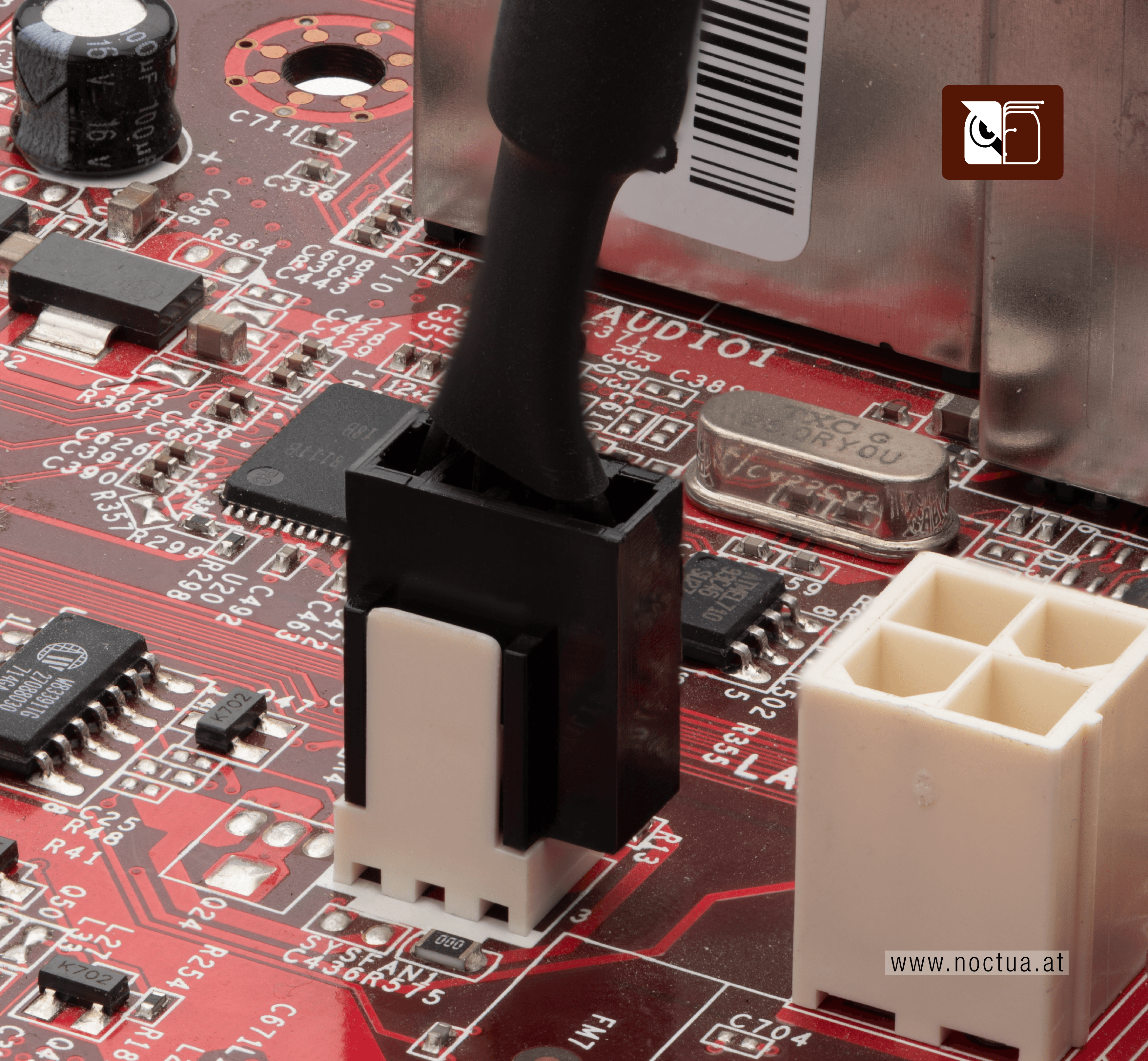 A 4-pin fan connector plugged into a 3-pin fan header on a red motherboard, with one pin on the connector overhanging and not connected to the header.