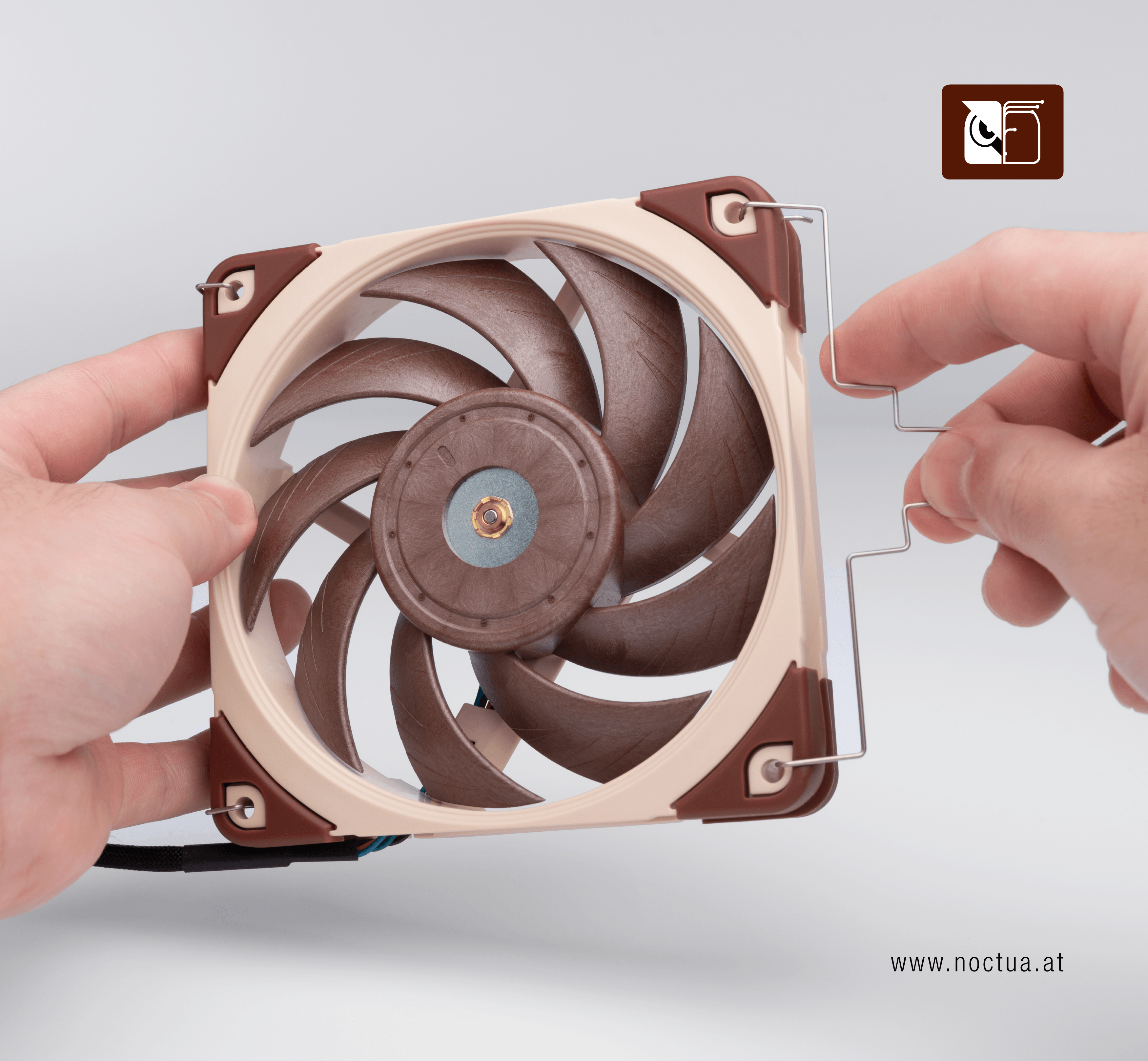 A fan is held in a hand, the other hand mounts a fan clip in two of the fans' mounting holes.