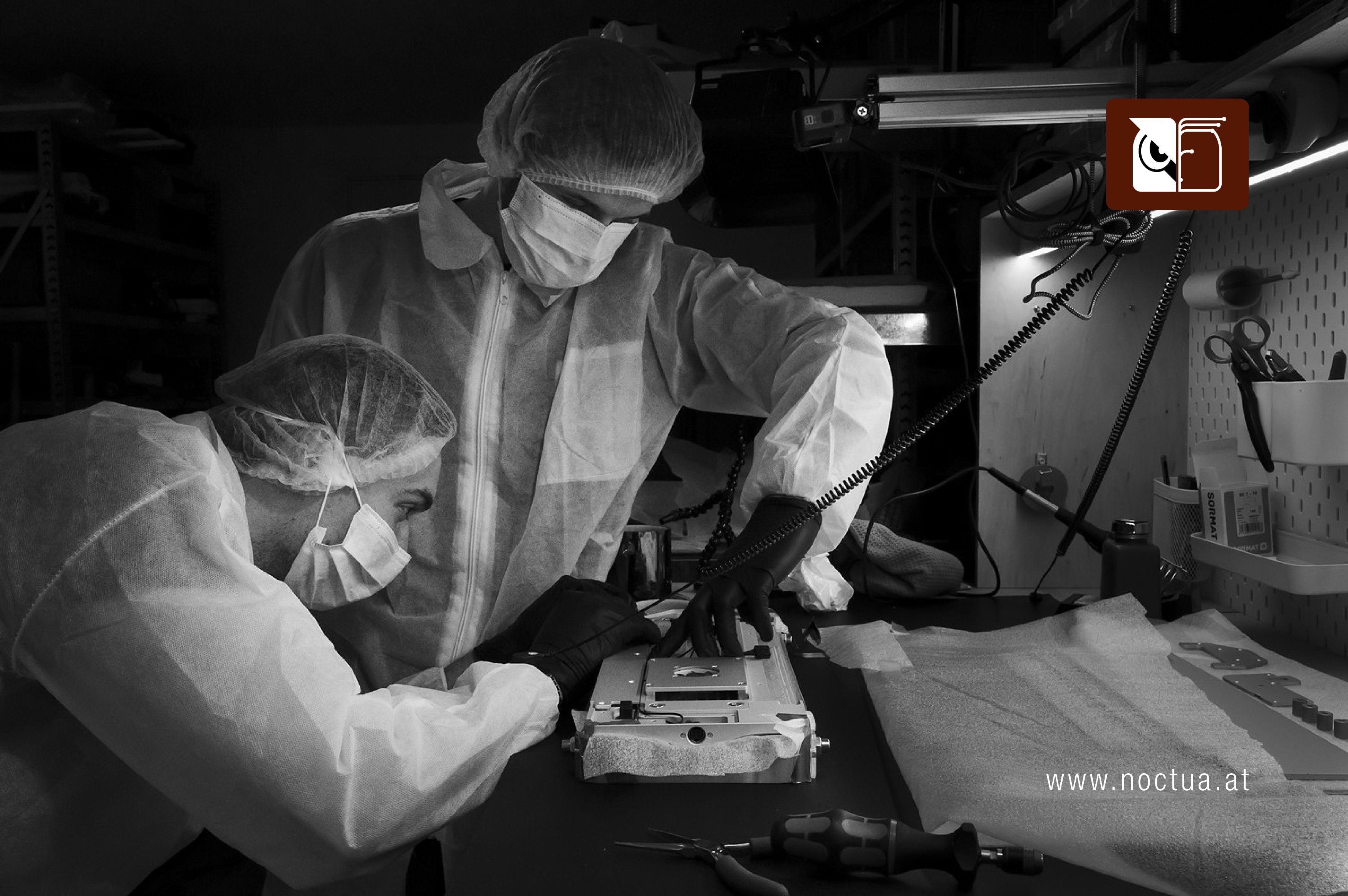 Two technicians in cleanroom suits assembling a SAGA Space Architects Circadian light module, featuring a Noctua fan, on a workbench.