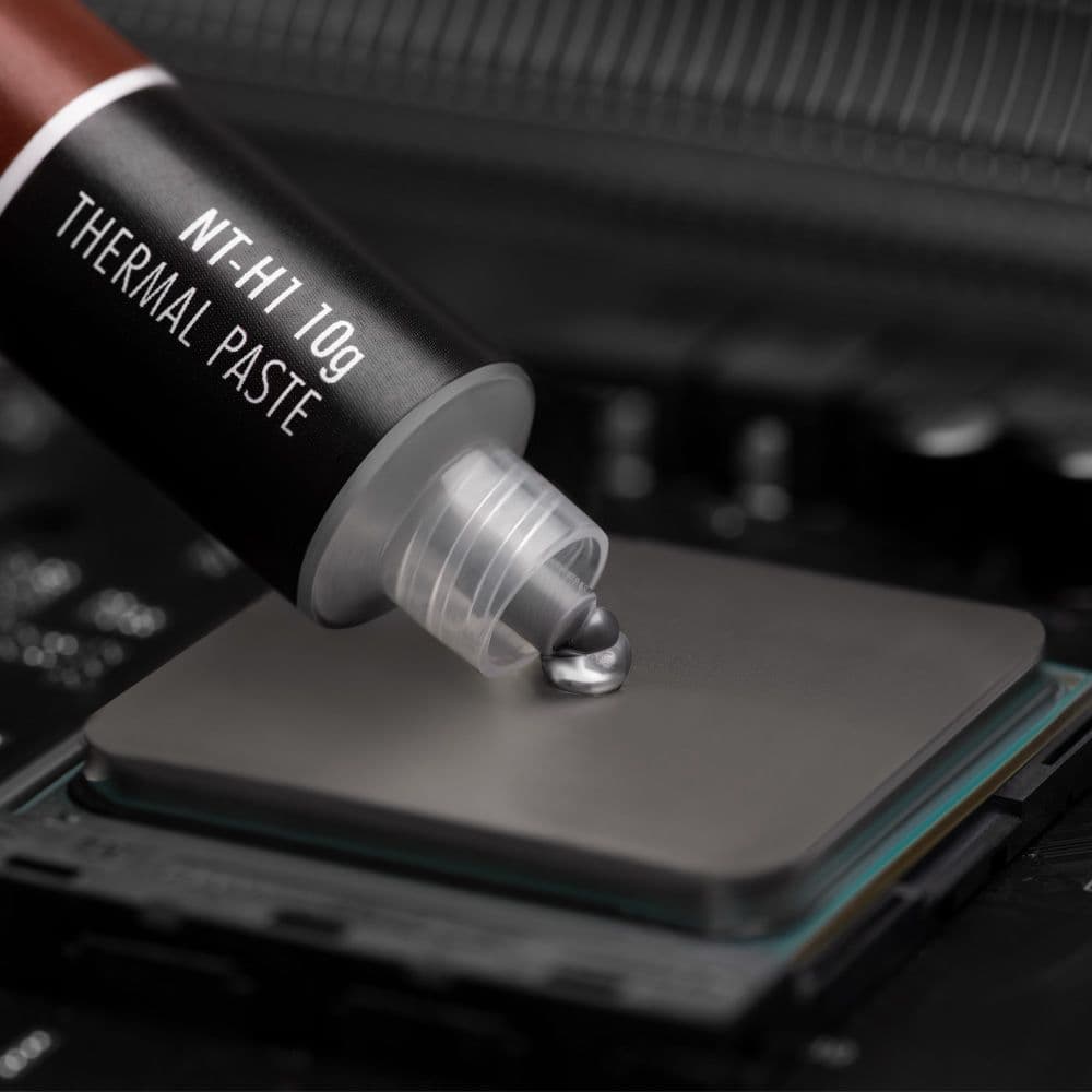A close-up shot of Noctua NT-H1 10g thermal paste being applied to the center of a CPU's heat spreader.