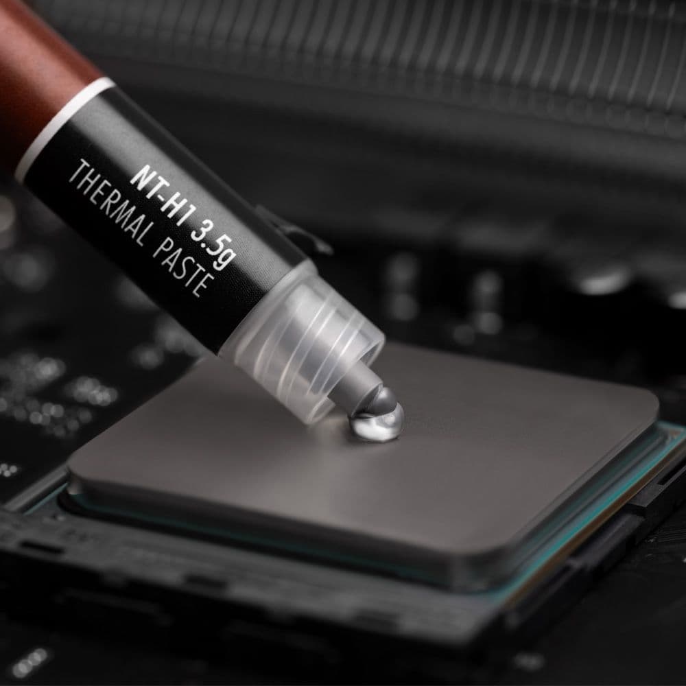 A close-up shot of Noctua NT-H1 3.5g thermal paste being applied to the center of a CPU's heat spreader.