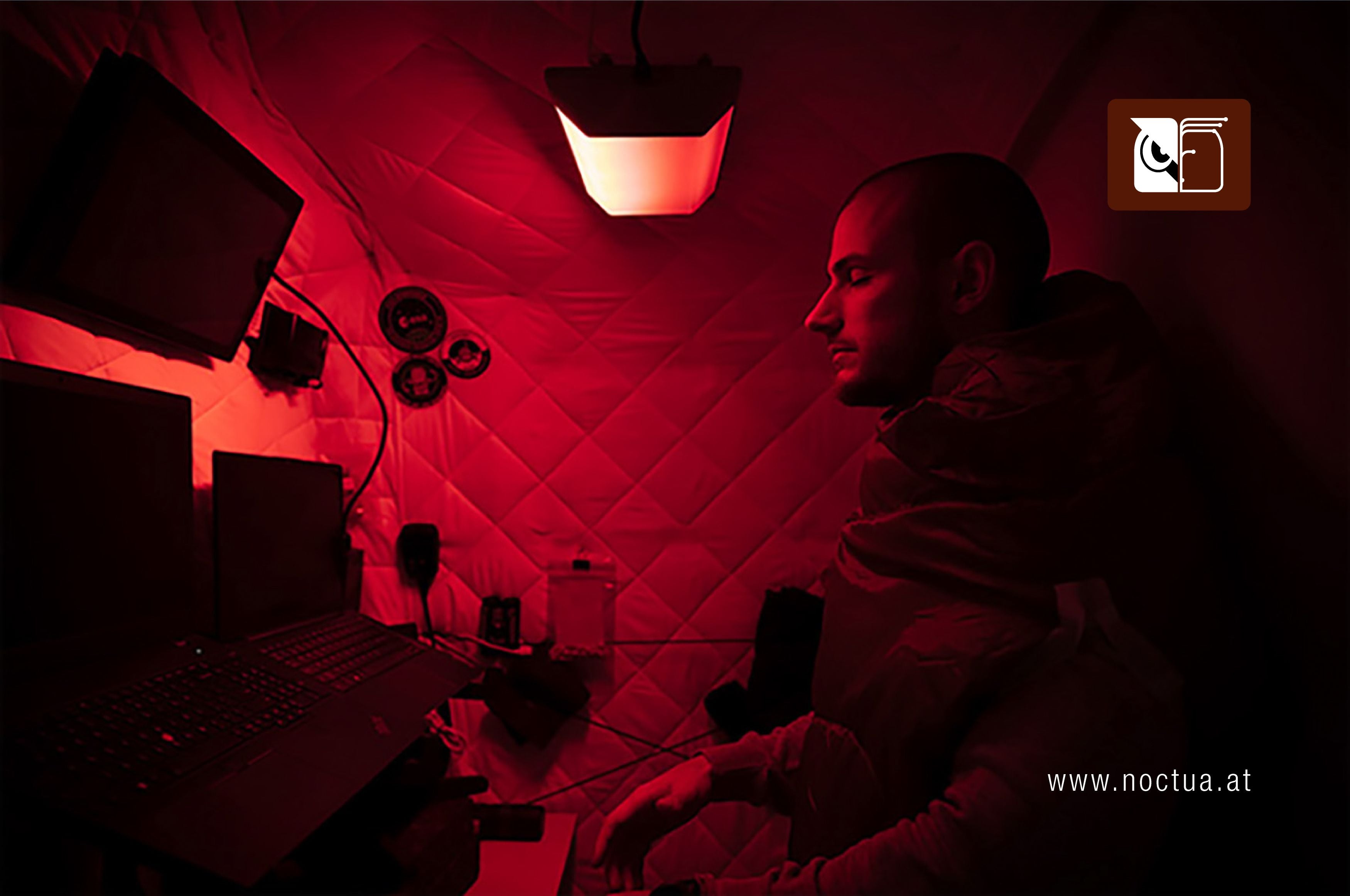 A man in a small space living quarters looking upwards at a Circadian light set to red color designed by SAGA Space Architects mounted above his head.
