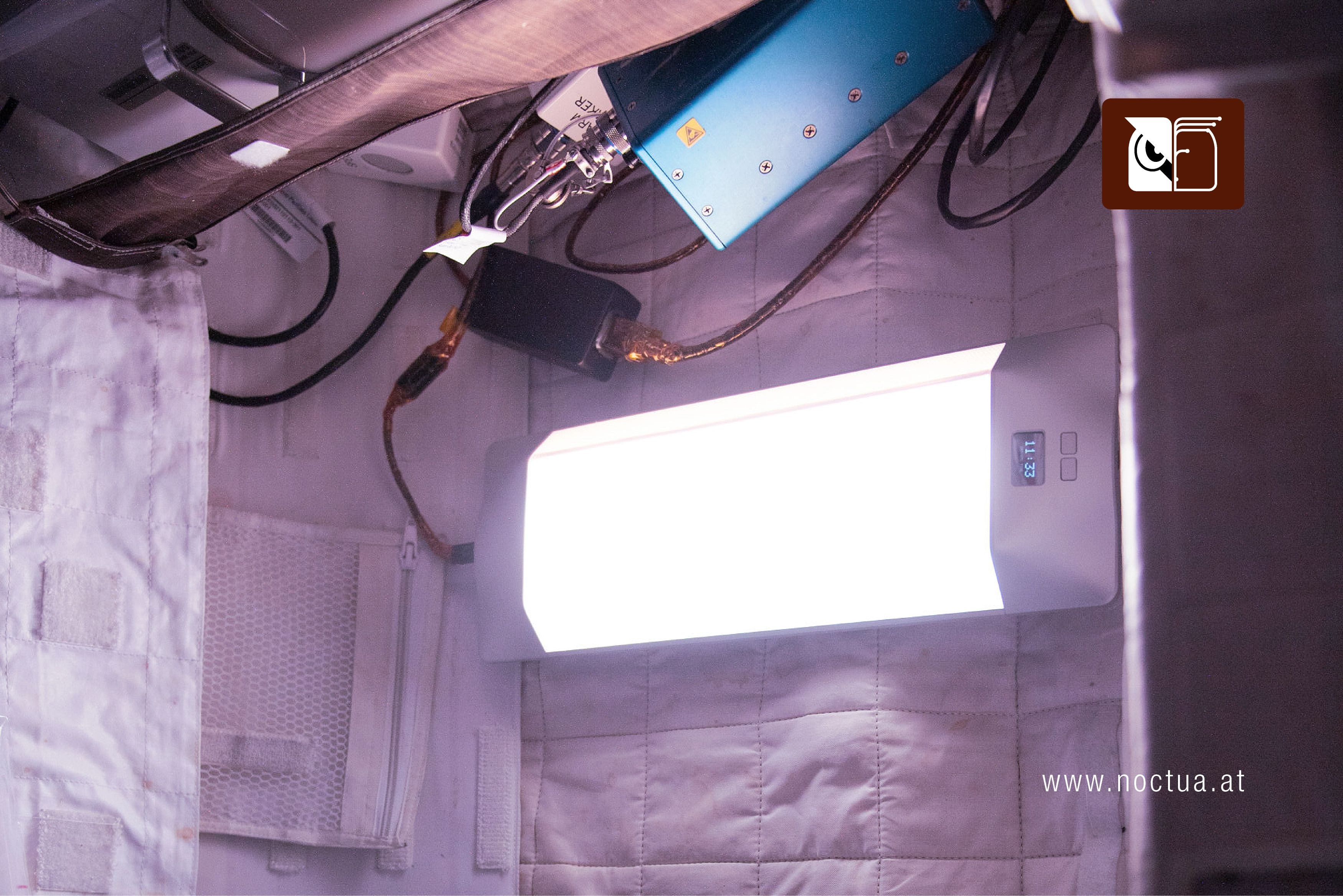 Wall-mounted SAGA Circadian light emitting white light in a room that looks like small living quarters on a space station.